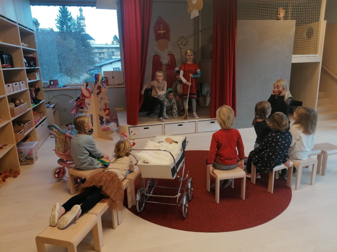 Rollenspiel wird von zwei Kindern vorgespielt. Die anderen Kinder sitzen in einem Stuhlkreis rundherum und hören interessiert zu.