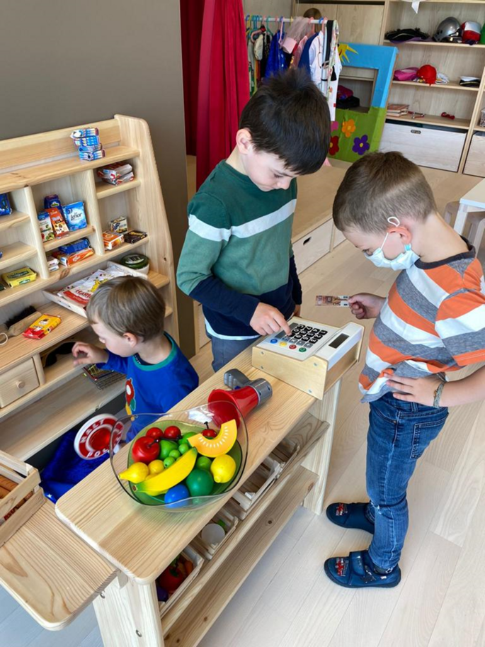 Drei Jungs spielen Einkaufen mit Falschgeld, Plastikessen und Spielen.