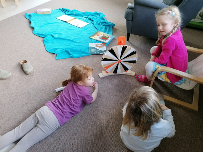 Drei Mädchen spielen ein Spiel mit einem Drehrad.